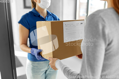 Image of delivery girl in face mask giving parcel to woman