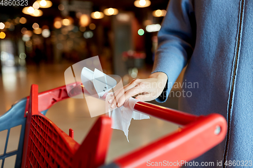 Image of hand cleaning shopping cart handle with wet wipe