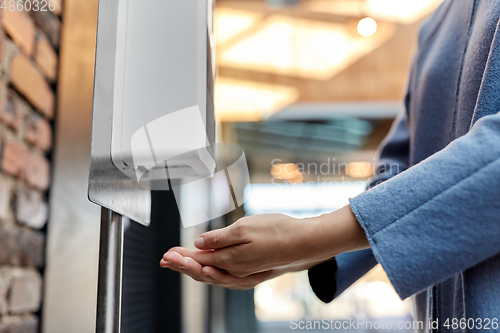 Image of close up of woman at dispenser with hand sanitizer