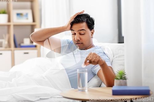 Image of sick man in bed with medicine and glass of water