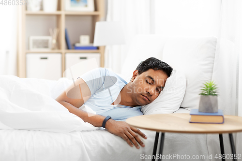 Image of indian man with tracker sleeping in bed at home