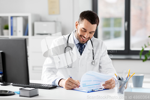 Image of smiling male doctor with clipboard at hospital