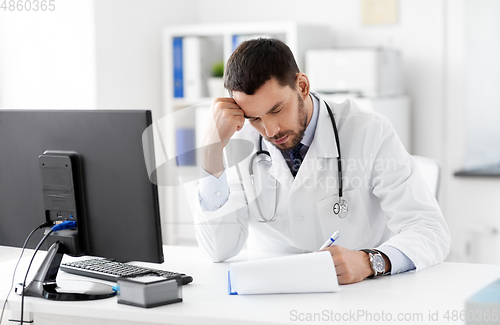 Image of stressed male doctor with clipboard at hospital