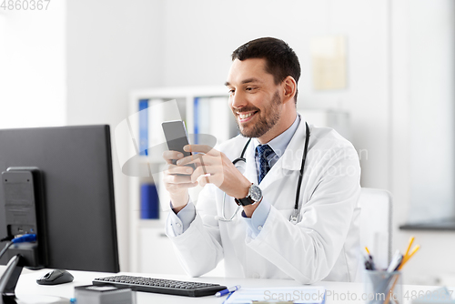 Image of smiling male doctor with smartphone at hospital