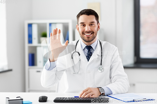 Image of happy male doctor waving hand at hospital
