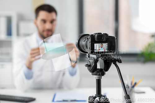 Image of doctor with mask recording video blog at hospital