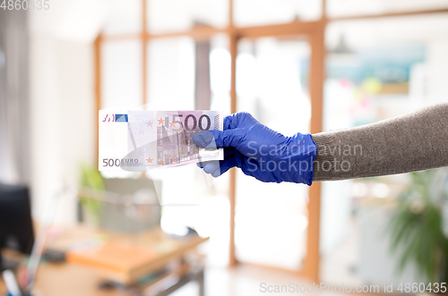 Image of close up of hand in medical glove with money