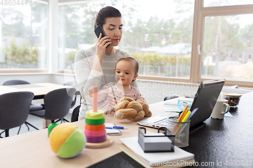 Image of mother with baby working on laptop at home office