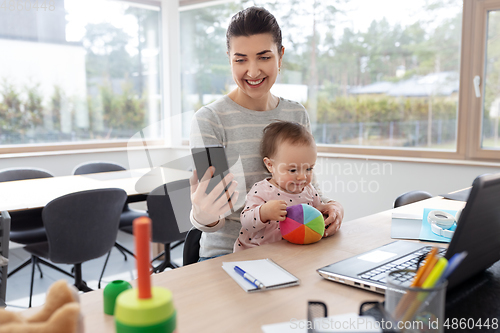 Image of mother with baby and phone working at home office