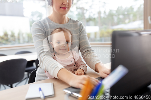 Image of mother with baby working on laptop at home office