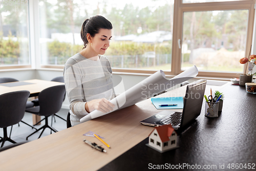 Image of young woman with blueprint working at home office