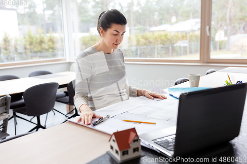 Image of young woman with blueprint working at home office