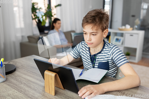 Image of student boy with tablet computer learning at home