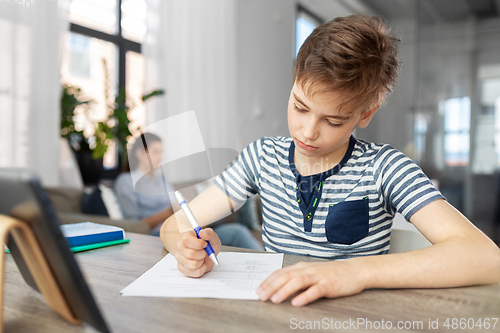 Image of student boy with tablet computer learning at home