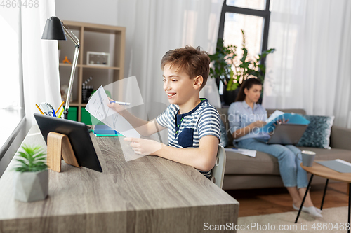 Image of student boy with tablet computer learning at home