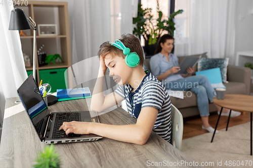 Image of sad boy with laptop and headphones at home