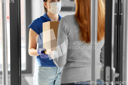 Image of delivery girl in face mask giving parcel to woman