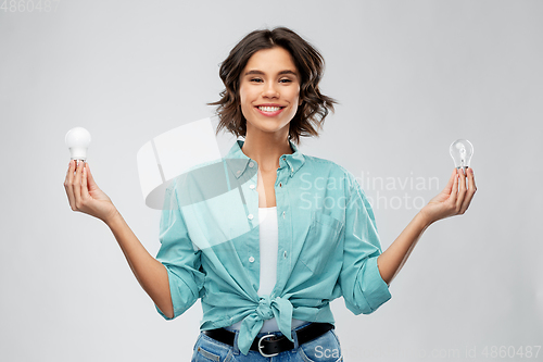 Image of smiling woman comparing different light bulbs