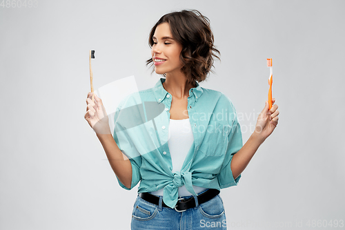 Image of woman comparing wooden and plastic toothbrush
