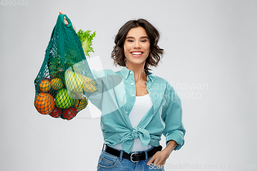 Image of happy smiling woman with food in reusable net bag