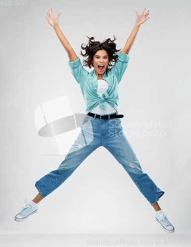 Image of happy young woman jumping over grey background