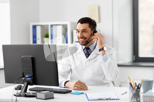 Image of happy doctor with computer and headset at hospital