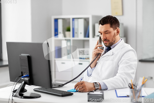 Image of male doctor calling on desk phone at hospital