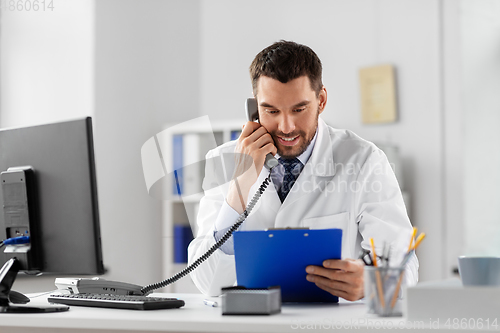 Image of male doctor calling on desk phone at hospital