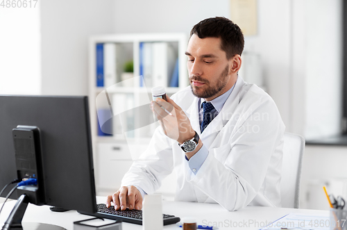 Image of male doctor with medicine and computer at hospital