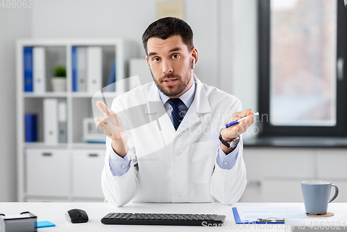 Image of doctor in earphones having video call at clinic