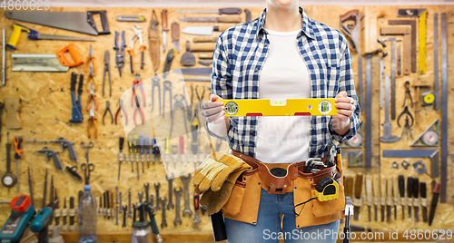 Image of woman builder with level and working tools on belt