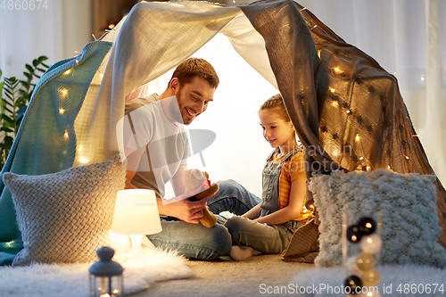 Image of happy family playing with toy in kids tent at home