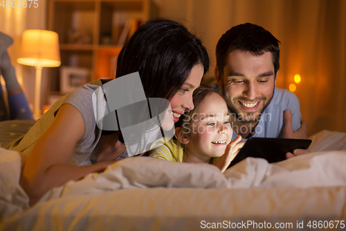 Image of family with tablet pc in bed at night at home