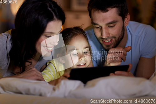 Image of family with tablet pc in bed at night at home