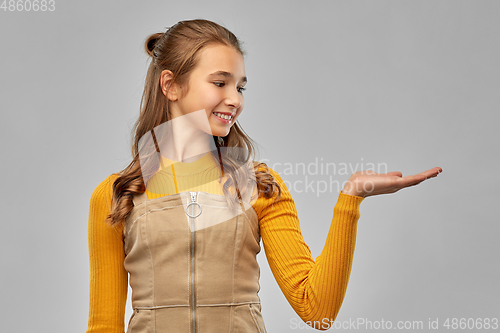 Image of happy teenage girl holding something on empty hand