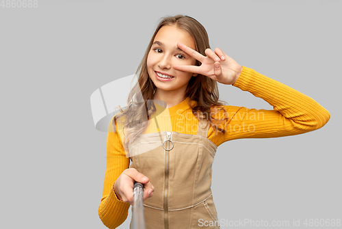 Image of happy teenage girl taking selfie and showing peace