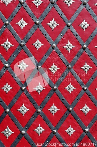 Image of Medieval red door with diagonal iron stripes and silver stars