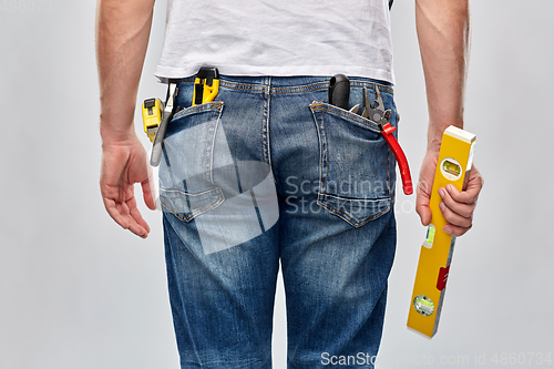 Image of man with level and working tools in pockets