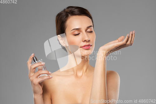 Image of happy woman smelling perfume from her wrist