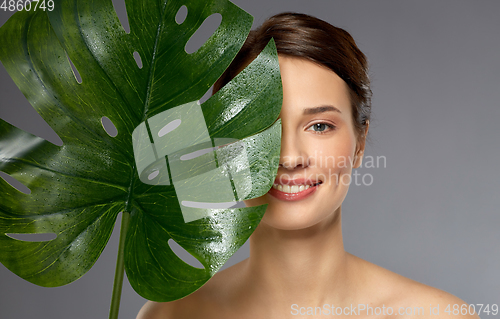 Image of beautiful young woman with green monstera leaf