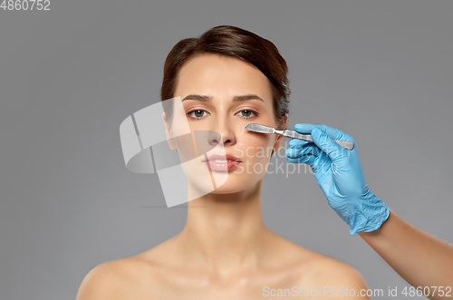 Image of beautiful young woman and hand with scalpel