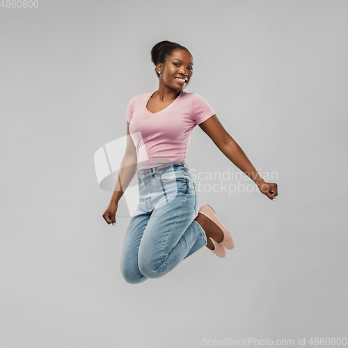 Image of happy african american woman jumping over grey