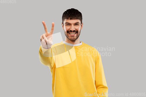 Image of young man showing peace over grey background