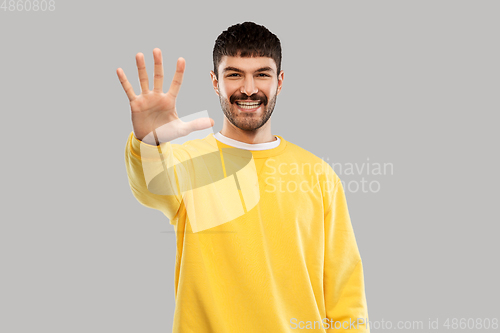 Image of smiling young man showing his hand or five fingers