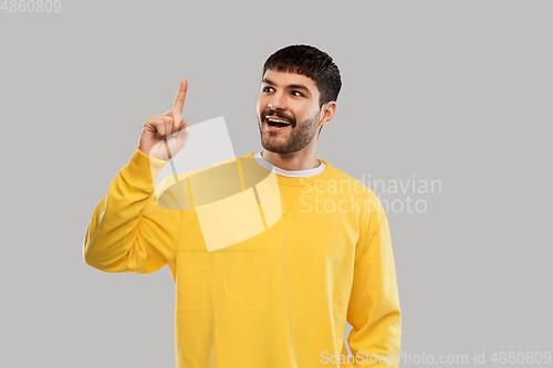 Image of young man showing one finger in yellow sweatshirt