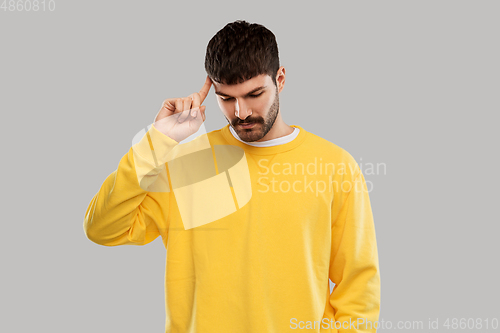 Image of thinking young man in yellow sweatshirt