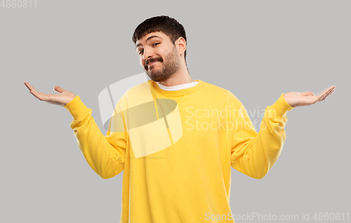 Image of confused man in yellow sweatshirt shrugging