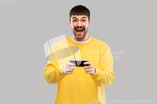 Image of happy laughing young man with smartphone