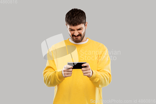 Image of displeased young man with smartphone