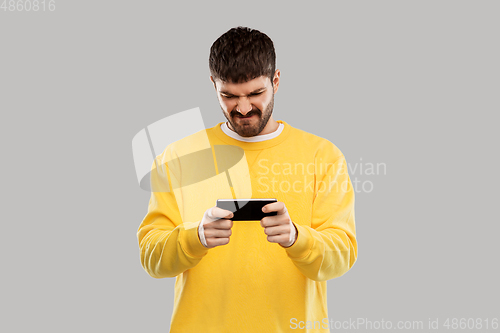 Image of displeased young man with smartphone